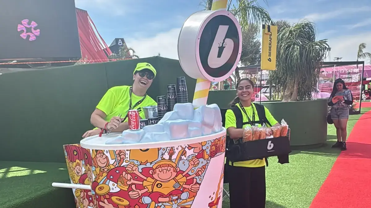 Equipo de venta móvil de BEBERAPID junto al carro en forma de vaso en Macondo Park