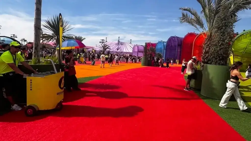 Alfombra roja y pabellones de colores de Macondo Park durante los conciertos de Shakira en Madrid, con un carro de venta móvil de BEBERAPID